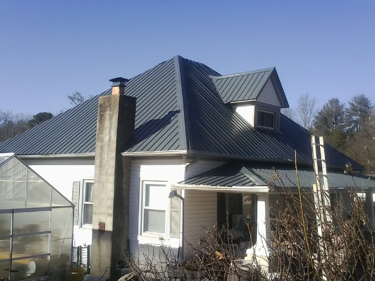 Dark blue standing seam metal roof on a white farmhouse with dormer — Slate & Tile Roof Repair by Roofing Brothers in Olivehurst