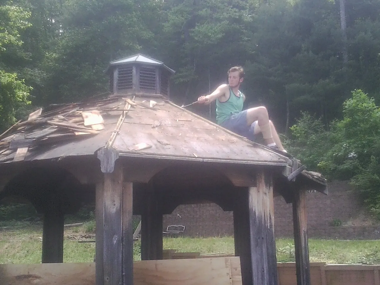 Tearing the old roof off a wooden gazebo before new shakes in Olivehurst
