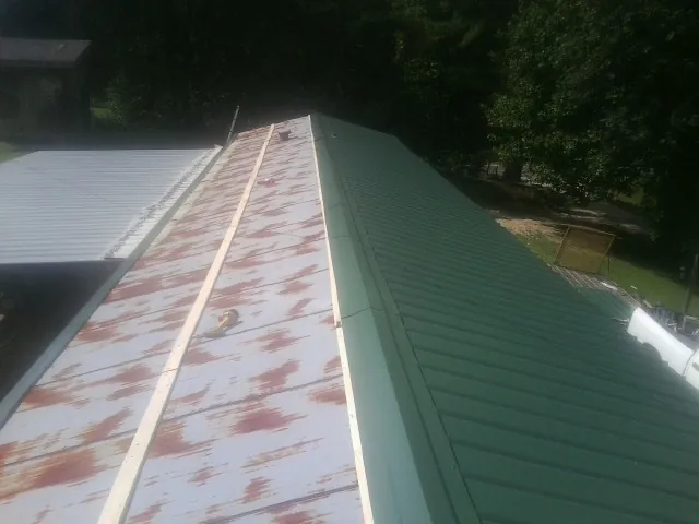 Old rusted panels beside newly installed green metal roofing — Wind Damage Roof Repair by Roofing Brothers in Olivehurst